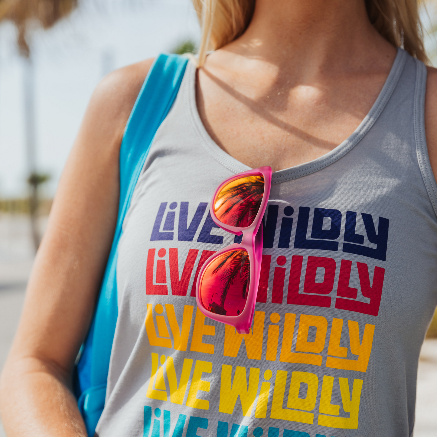 Live Wildly Polarized Sunglasses - Pink Pair Hanging On Tank Top - Live Wildly